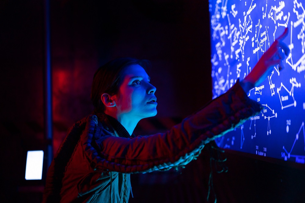 a woman in a spacesuit points at a screen