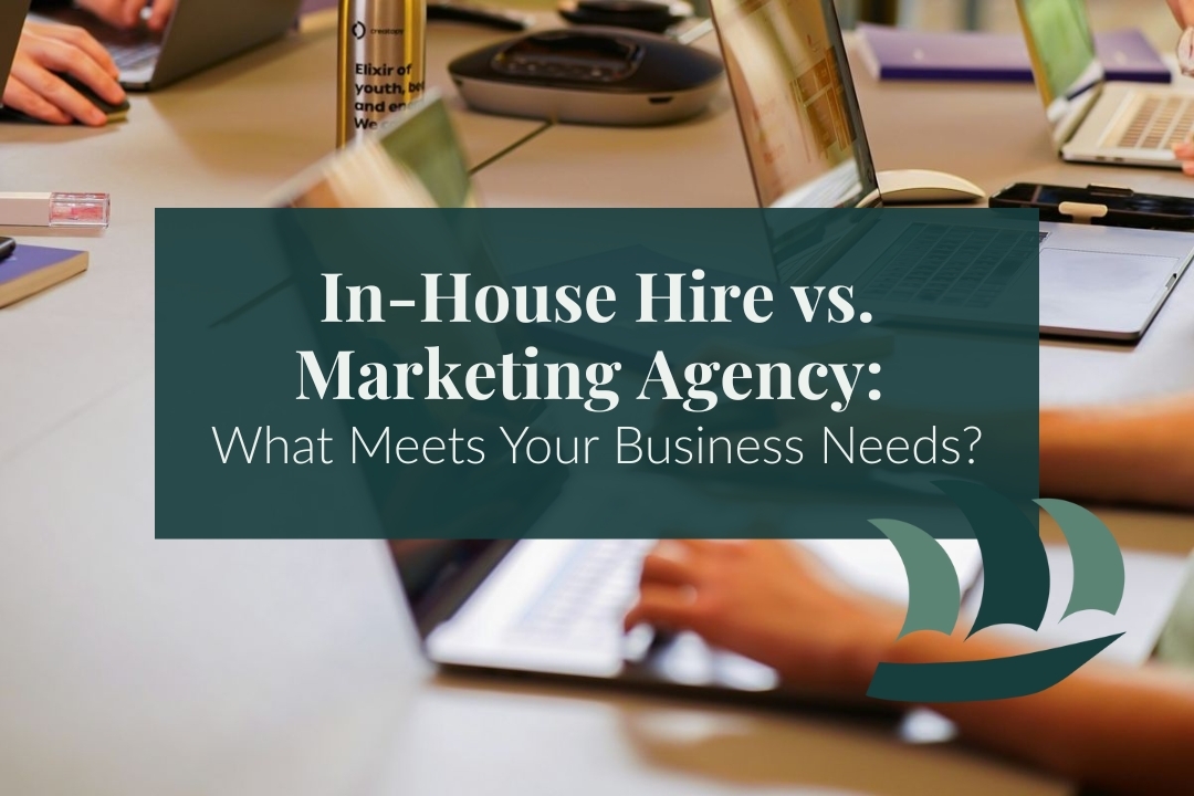 several laptops on a table at a marketing company with overlaid text that reads "In House Hire vs. Marketing Agency"